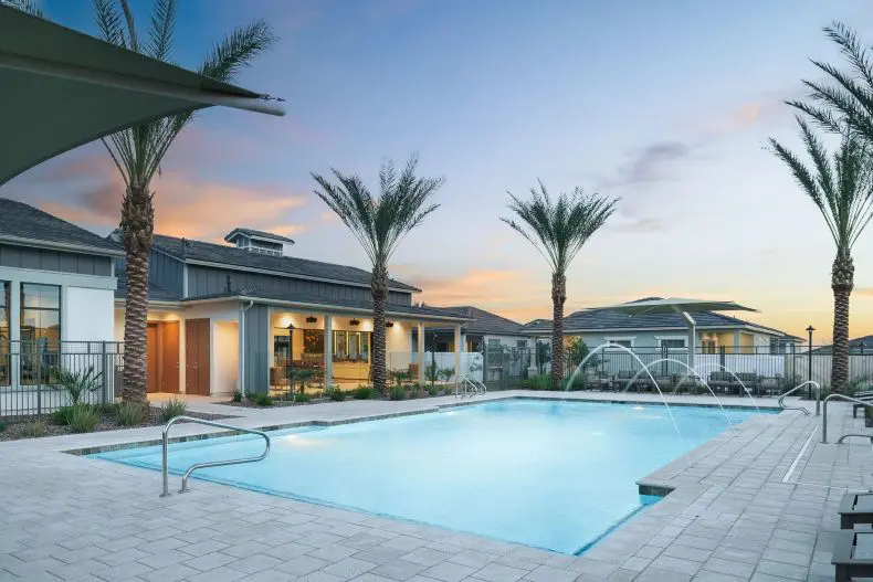 A pool with palm trees and a building in the background.